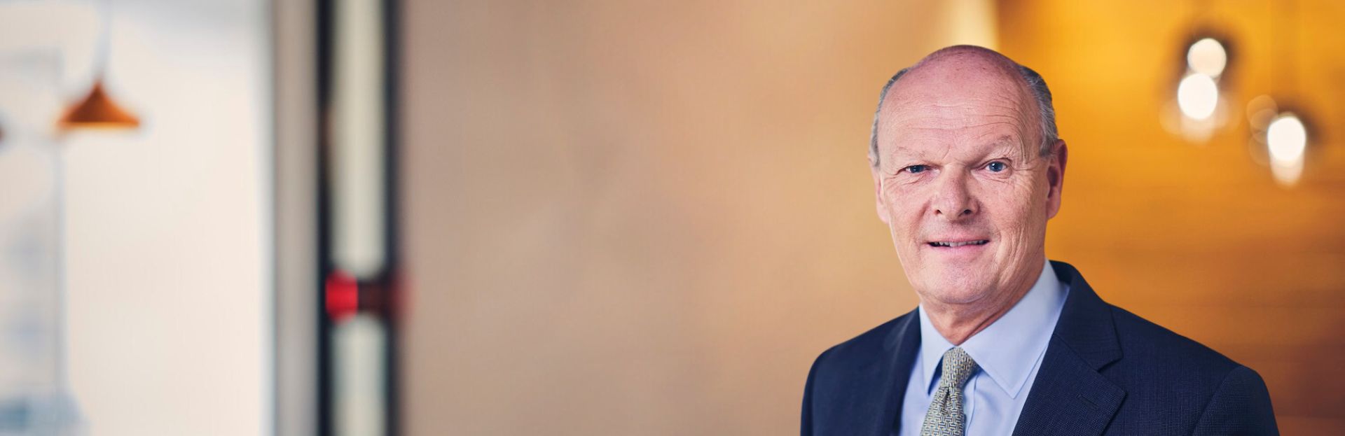 Man in a suit smiling in an indoor setting.