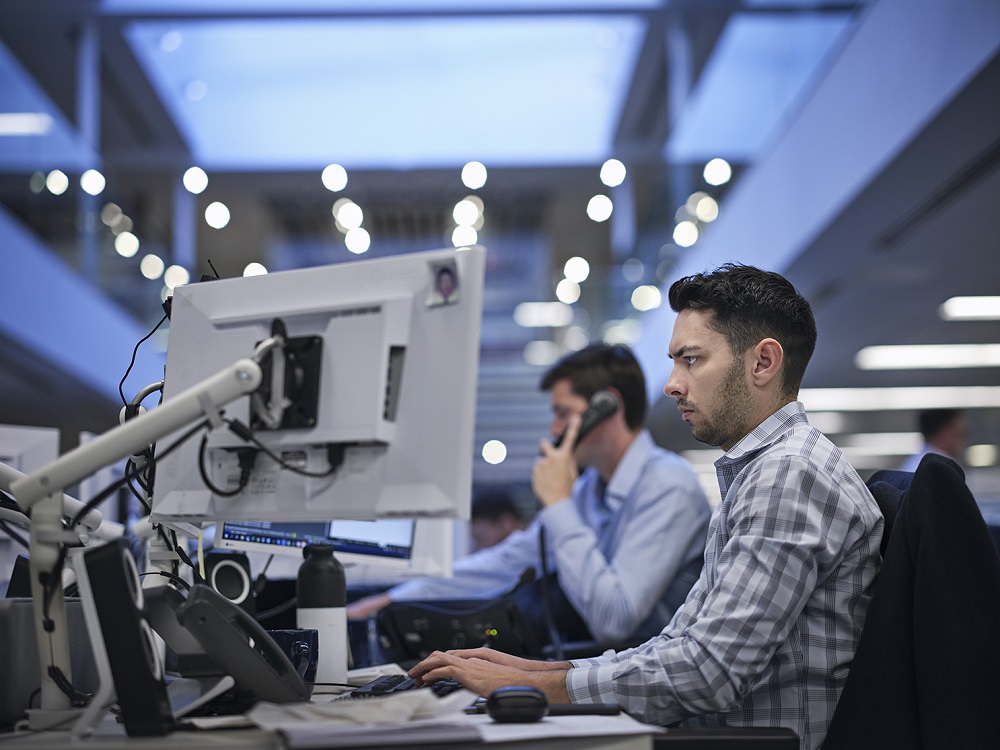 Man working at a desk with dual monitors.