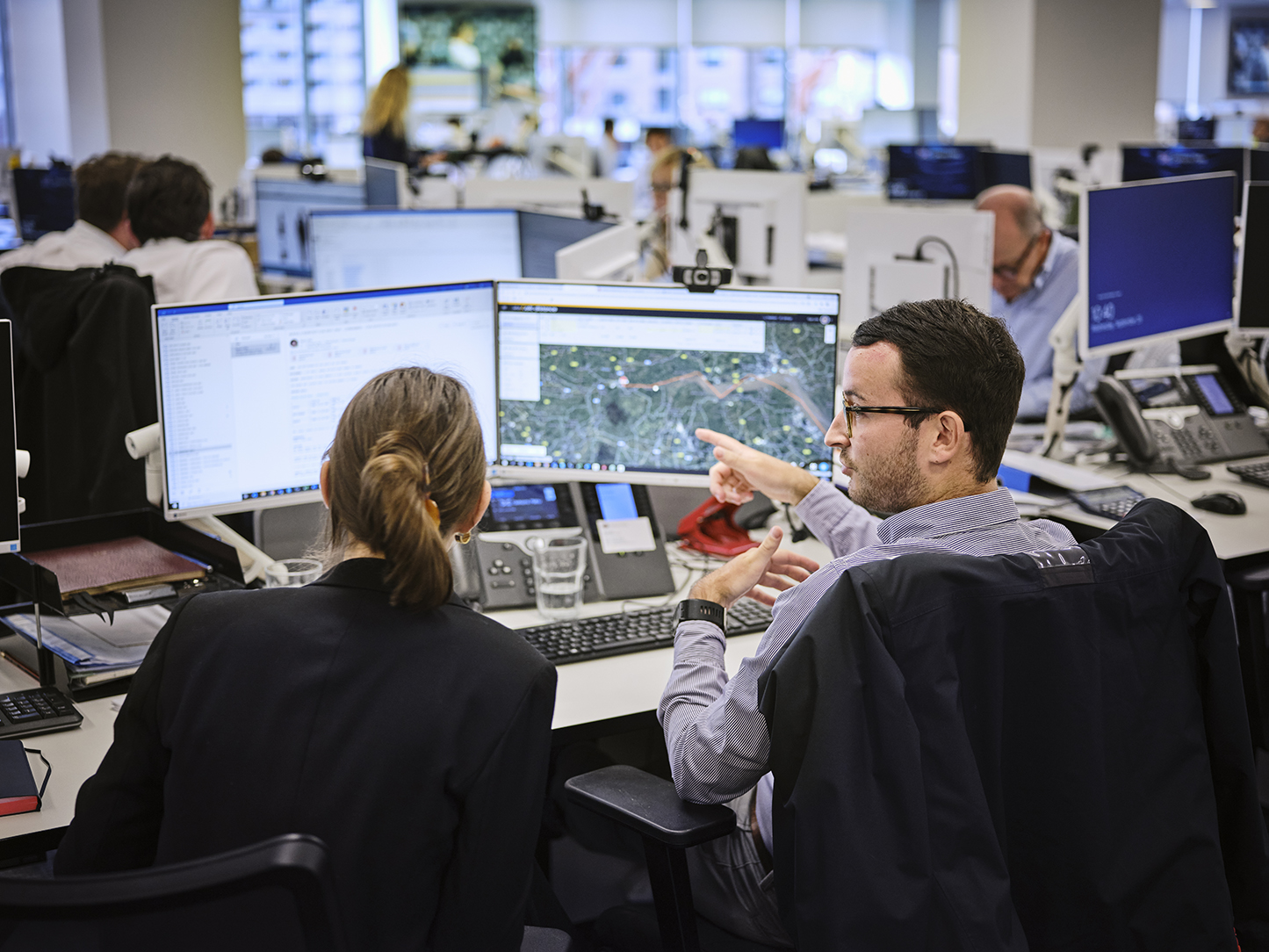 man at his desk explaining something on the screen to a female colleague