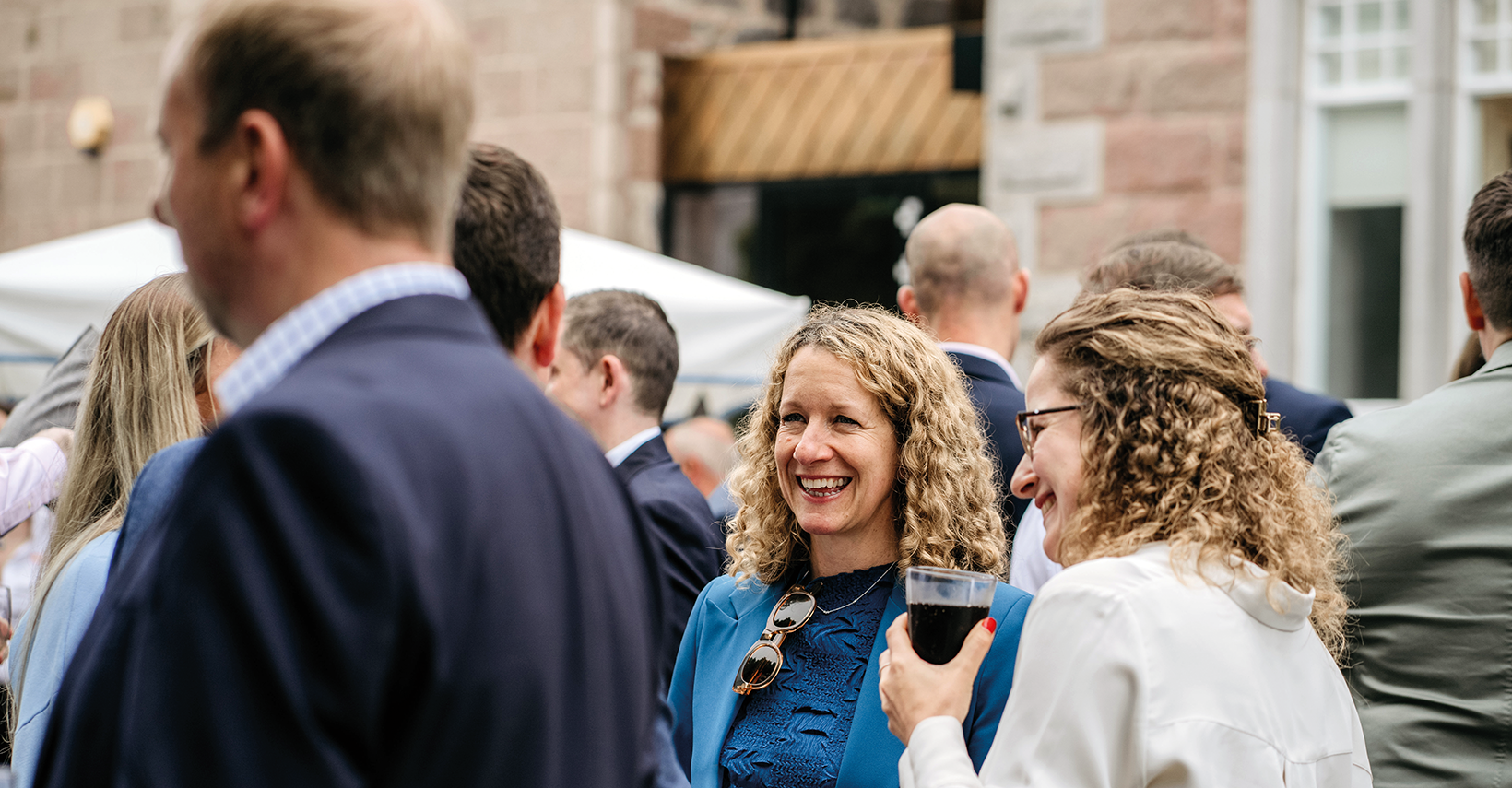 Group of people in conversation outdoors, focusing on two smiling women.