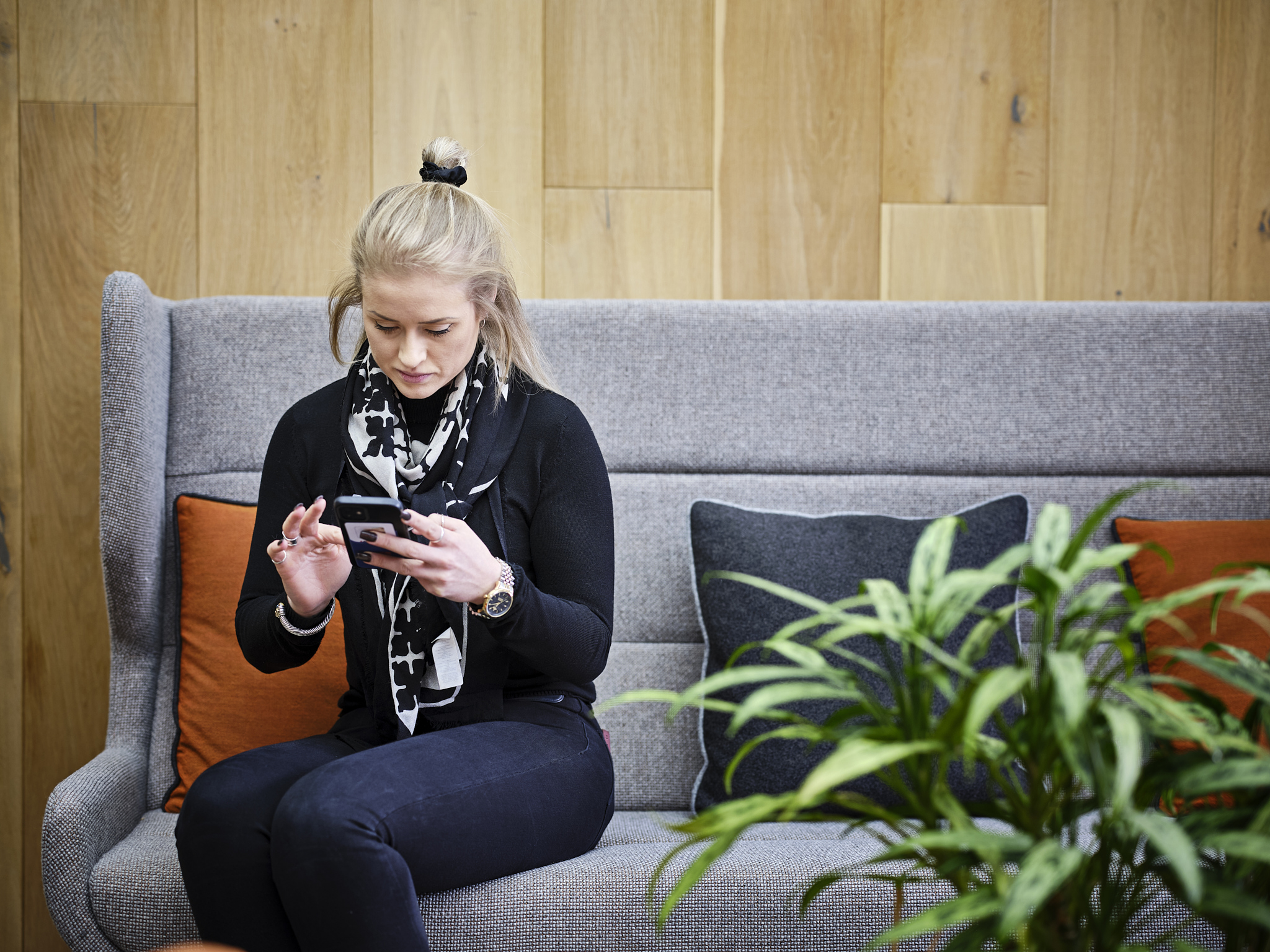 woman sitting on chair, looking down at her phone