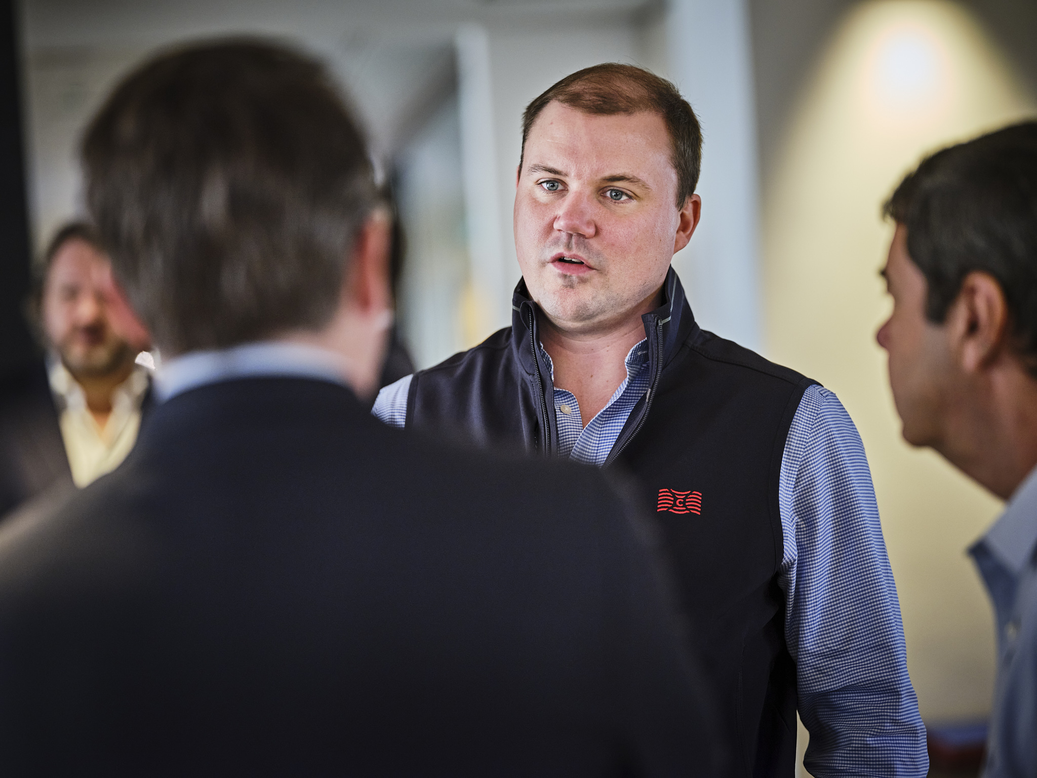 Group of men engaged in conversation indoors.