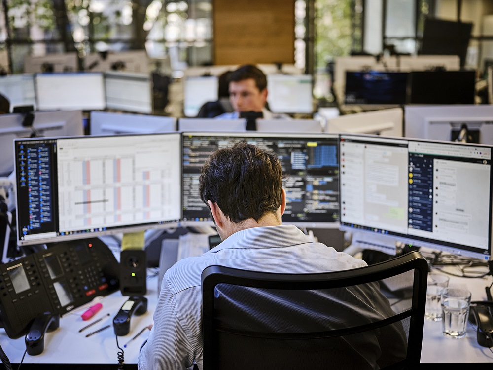 Person working at multiple computer monitors.