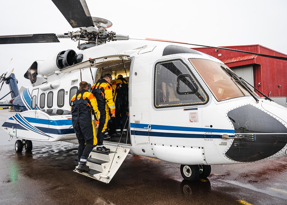 People in safety gear boarding a helicopter.