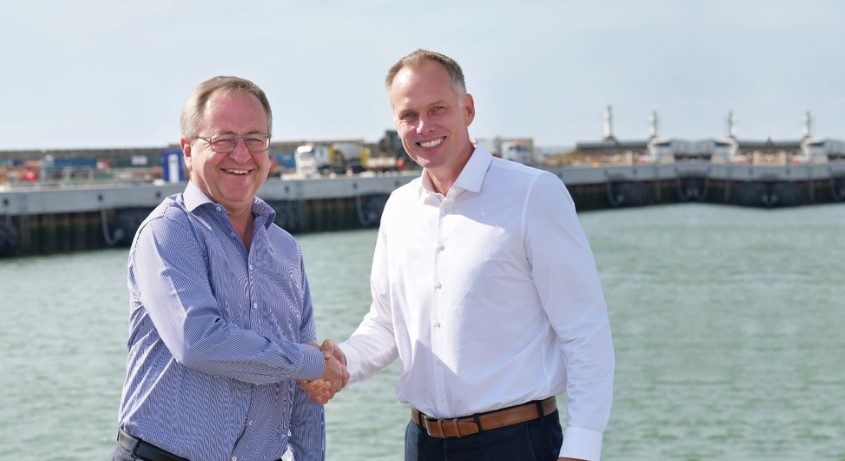 Two men shaking hands by the waterfront.