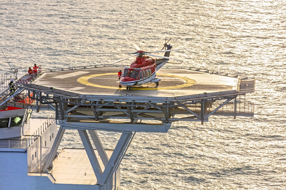 Helicopter on a helipad over the ocean.