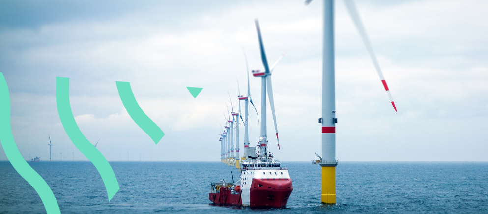 A ship next to wind turbines in the ocean.