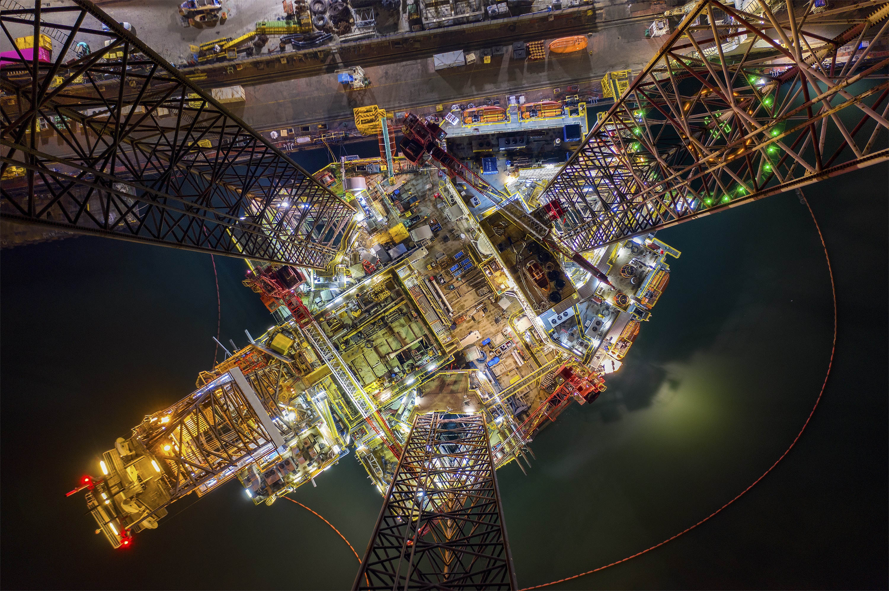 Oil and gas jack-up rig at the yard for maintenance with many vessels in the night time, the petroleum rig is applied for producing oil and gas in offshore in the petroleum industry
