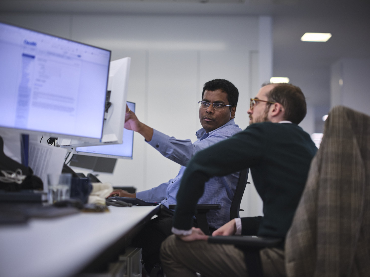 man pointing at his screen explaining to colleagues