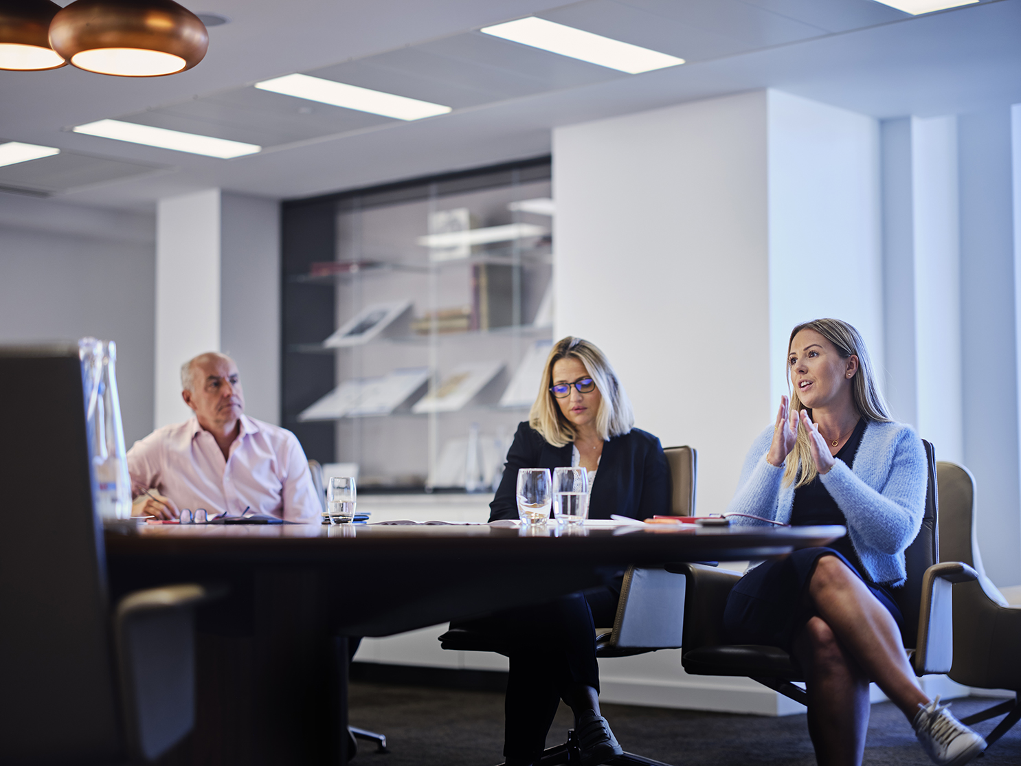 woman talking in a meeting with two other colleagues