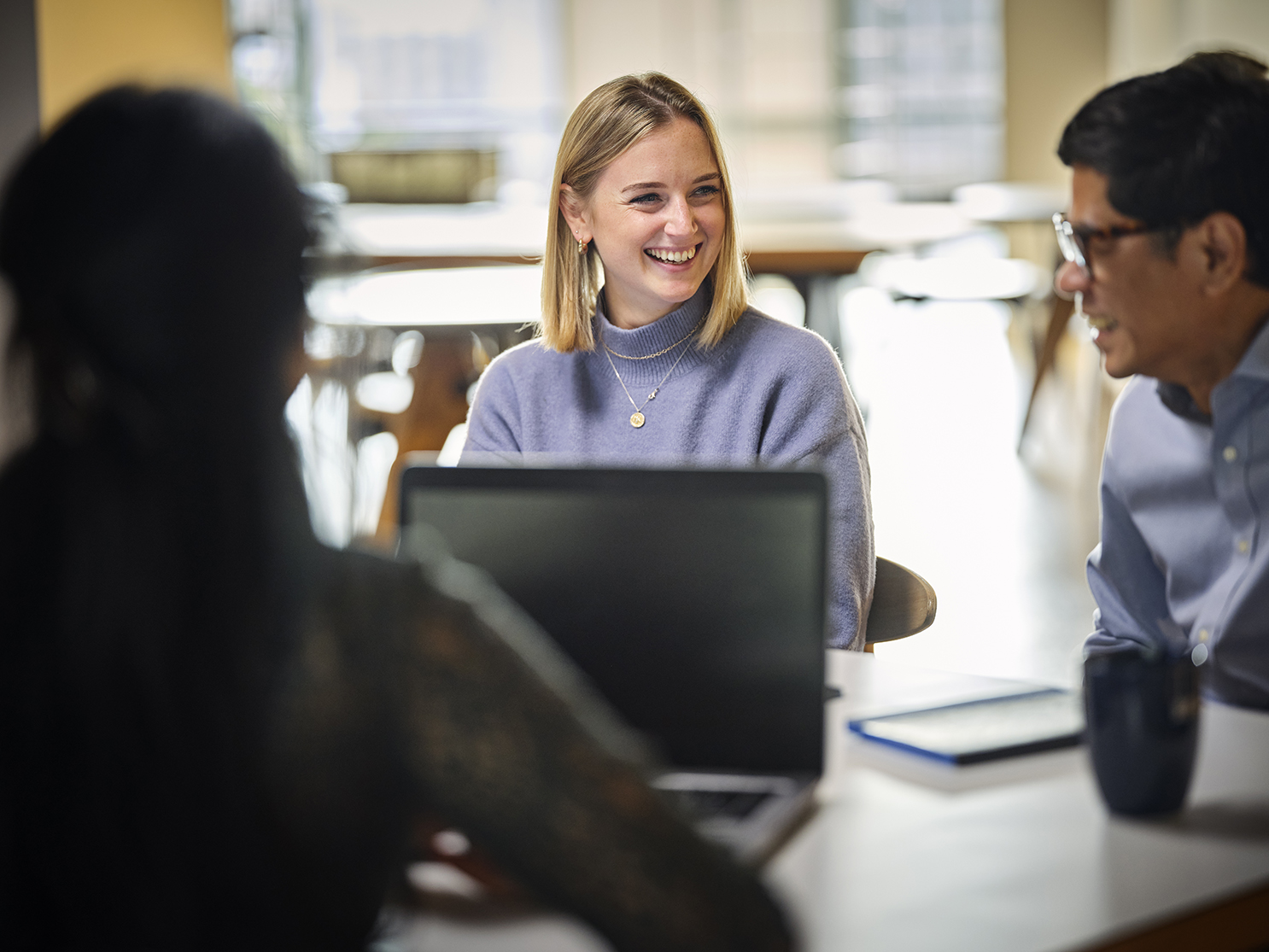 woman sitting at a table with colleagues smiling and talking