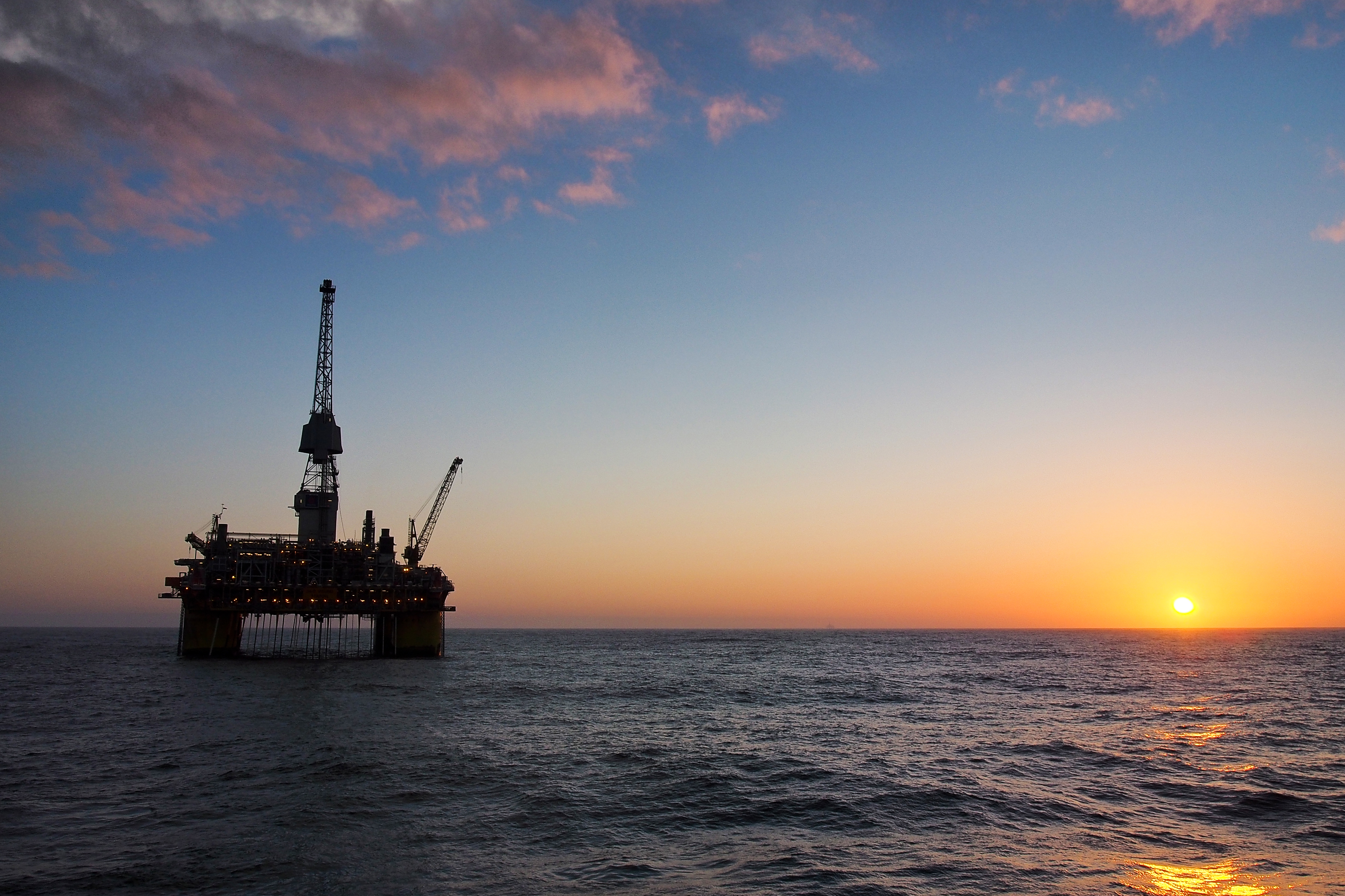 Oil rig silhouetted against a sunset.
