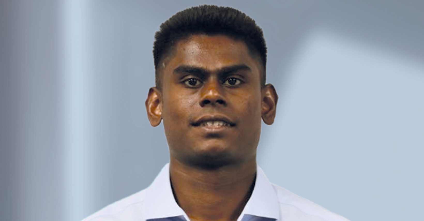 Young man with dark hair in a light blue shirt looking at the camera.