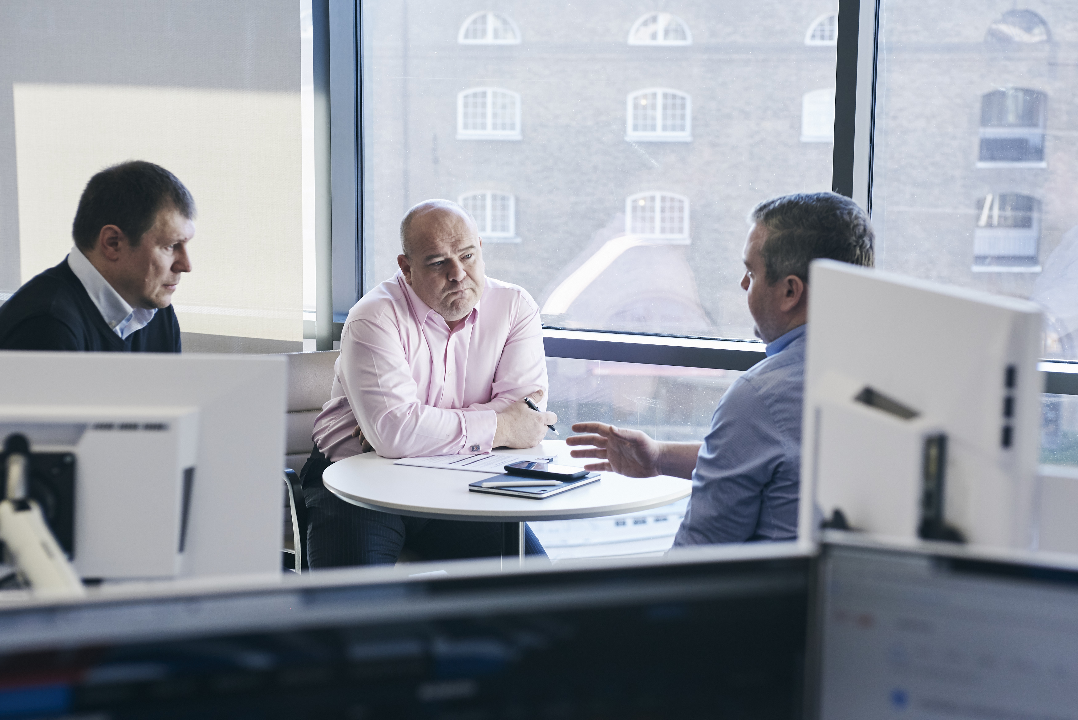 three men discussing work around a table