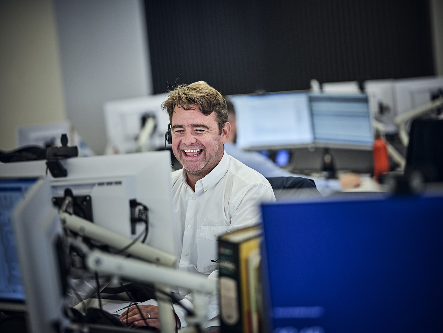 man laughing on the phone with his headset in the office
