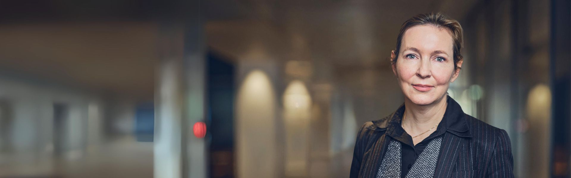 Woman in a blazer standing in a modern interior.
