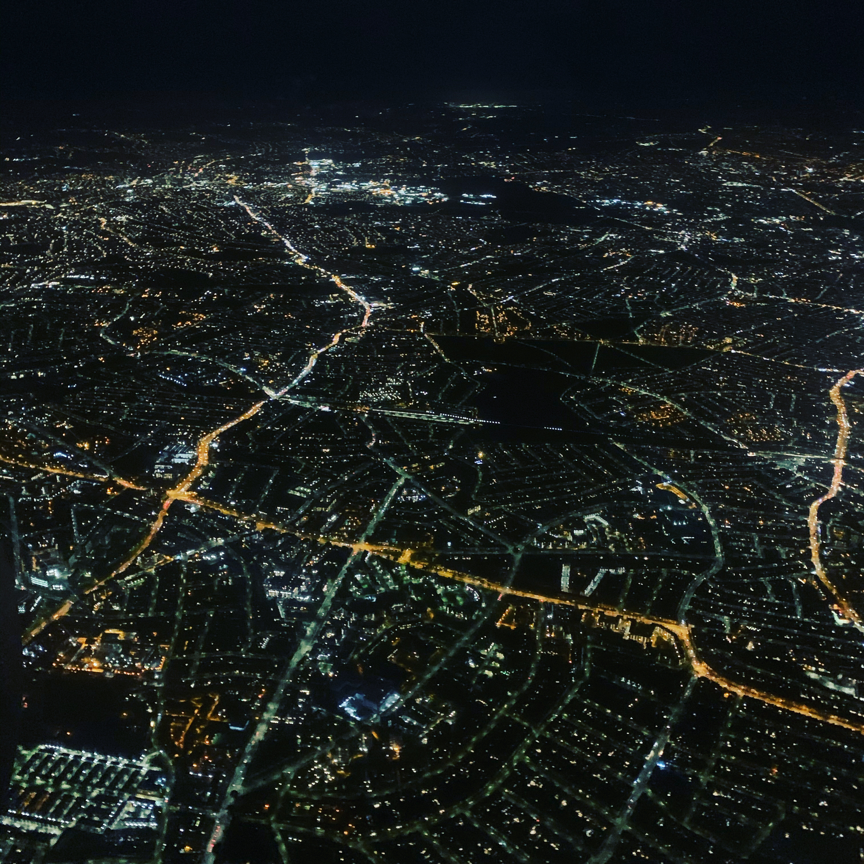 City lights illuminate streets at night from above.
