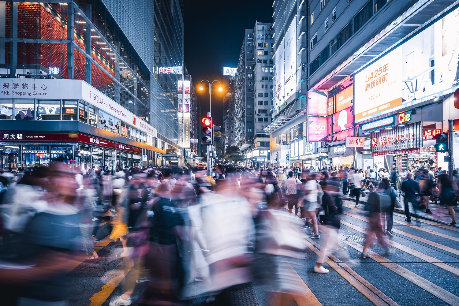 Busy street at night with blurred pedestrians.