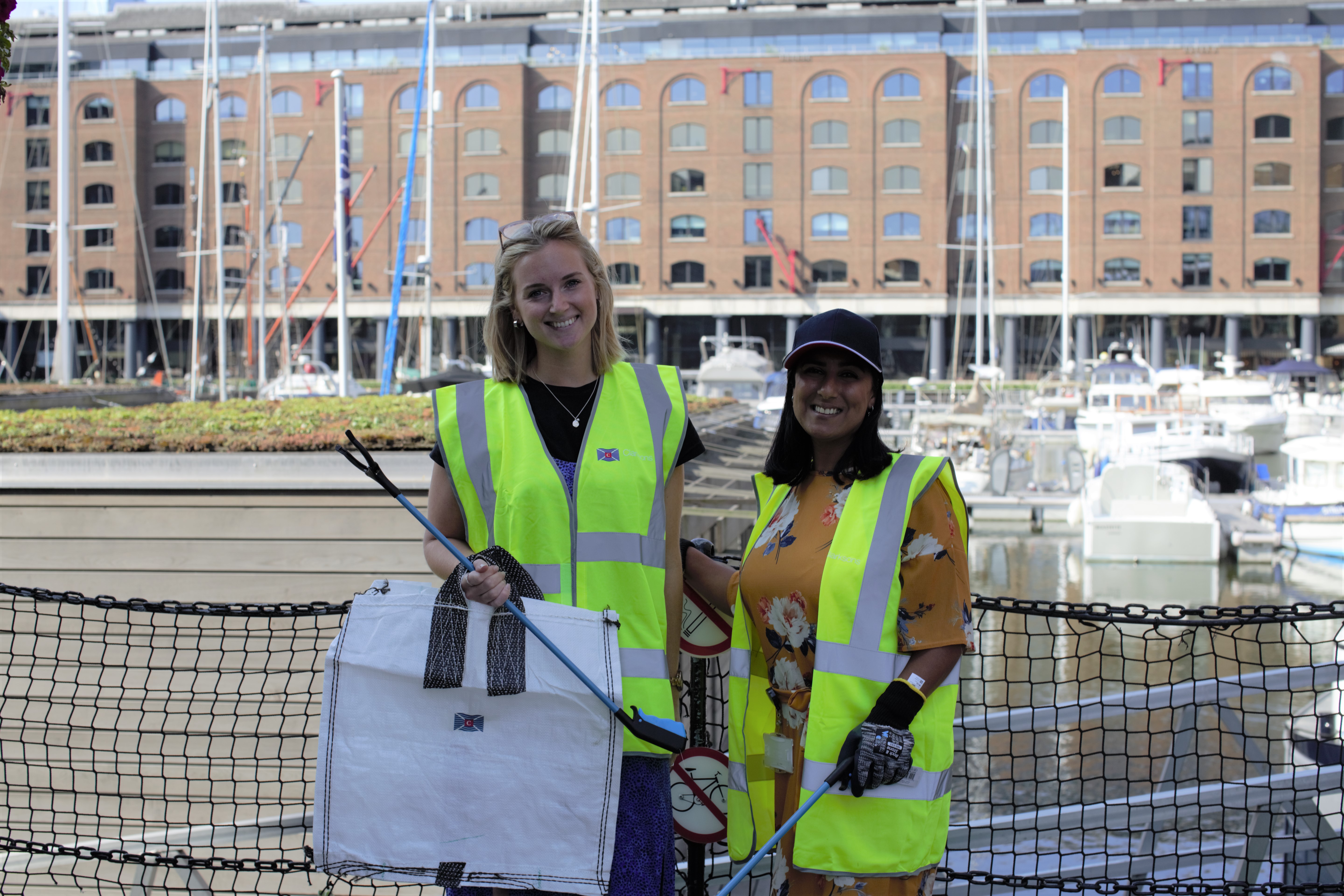 Two Clarksons employees in florescent jackets picking up litter