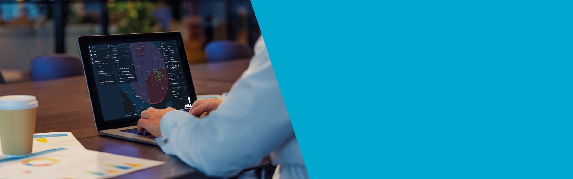 Person using a laptop on a table with a cup.