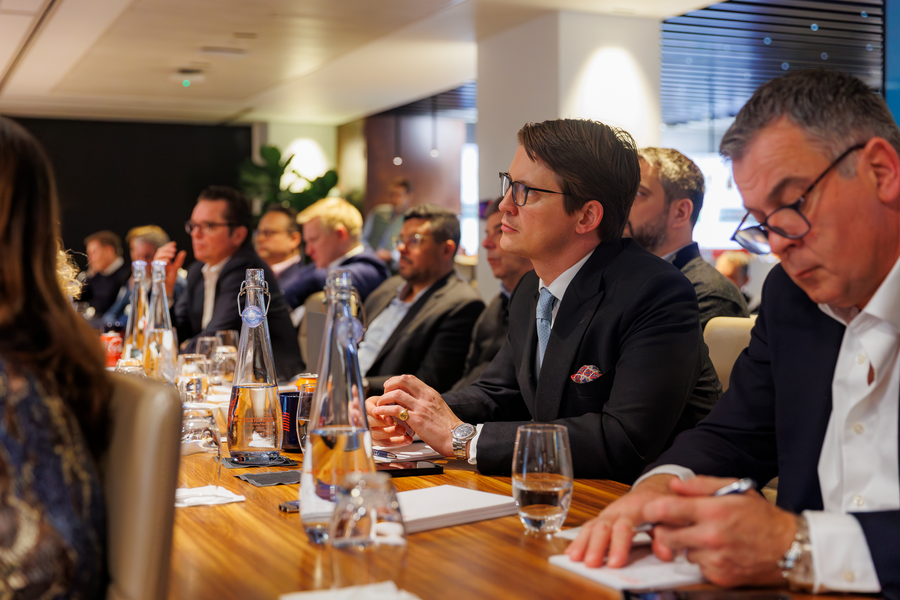 Group of people in business attire seated around a table for a discussion/presentation.