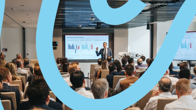 Speaker presenting to an audience with charts displayed.