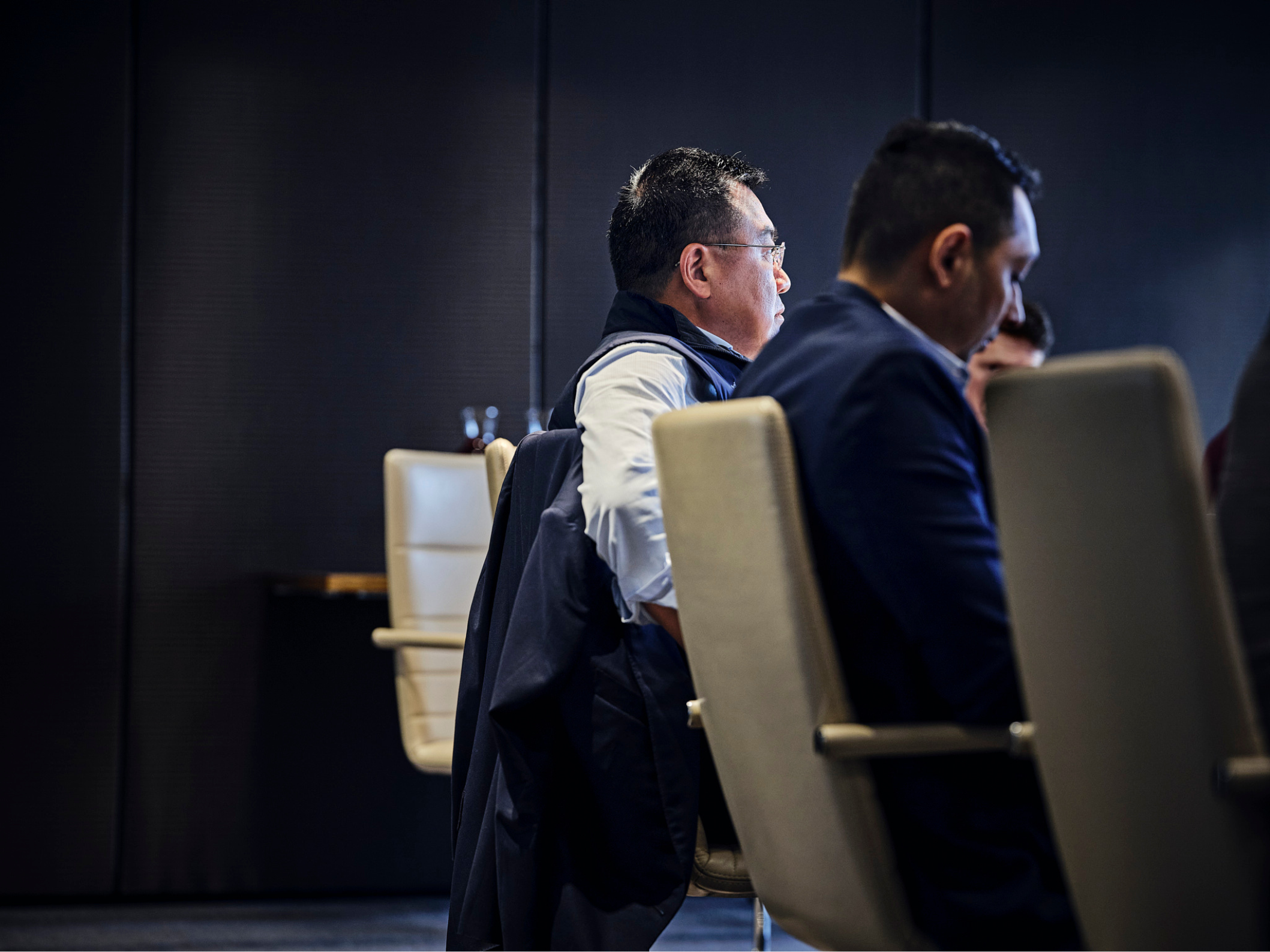 man in meeting, dark room, sitting in chair